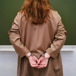 Person in handcuffs facing a chalkboard