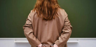 Person in handcuffs facing a chalkboard