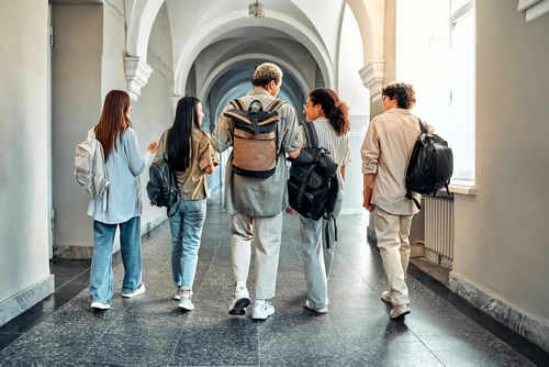 Five students walking in a school hallway together