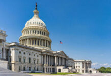 U.S. Capitol building with American flag, blue sky.