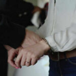 Shocking Arrests: Hospice Scheme Busted Person in handcuffs wearing jeans and white shirt