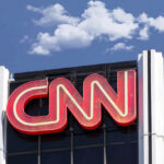 CNN building sign against blue sky with clouds.