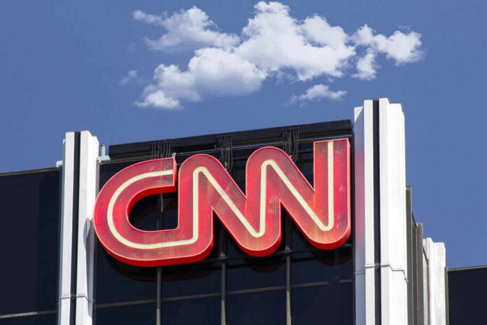 CNN building sign against blue sky with clouds.