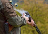 Person reloading shotgun outdoors with cartridges ejecting