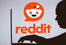 Silhouette of a person using a laptop in front of the Reddit logo