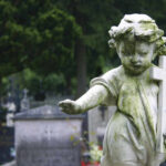 Mayor’s Promise: Never Forget the Shreveport Eight Weathered angel statue holding a cross in a cemetery
