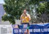 Speaker in yellow floral shirt addresses crowd at outdoor rally