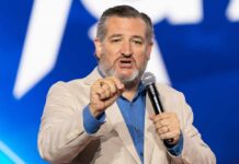 A man in a light suit speaking passionately into a microphone