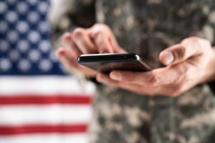 Soldier,Holding,Mobile,Phone.,Military,War,Espionage Aerial view through night vision targeting display.