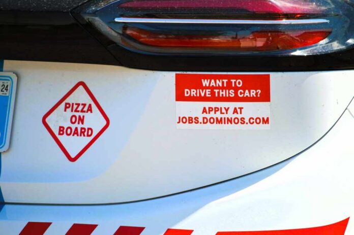 Car with pizza delivery signs and job advertisement