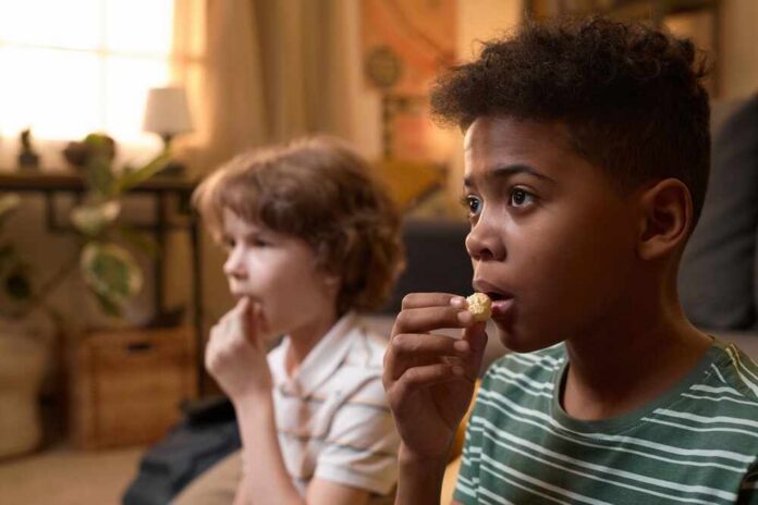 Two,Diverse,Children,Sitting,On,Floor,Eating,Popcorn,While,Watching Entrance canopy of a government office building