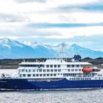 A cruise ship sailing in front of snow-capped mountains