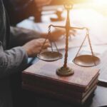 A set of legal scales on top of law books with a person working in the background