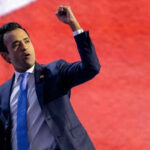 Man in suit raising fist on stage.