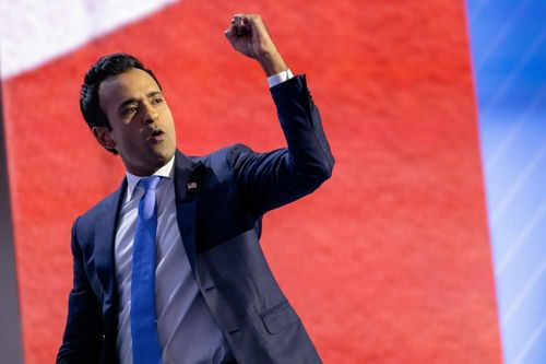 Man in suit raising fist on stage.