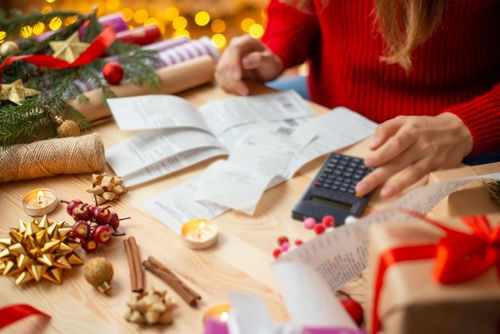 christmas-saving2234796279 Person calculating expenses with receipts and decorations