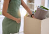 Pregnant woman packing items in cardboard box