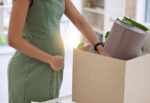 Pregnant woman packing items in cardboard box