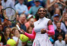 Tennis player smiling holding racket on court