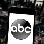 Trump Targets ABC—Another Payout Looming? A smartphone displaying the ABC logo against a blurred urban background