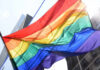 Public Decency Clash: Rainbow Flag Targeted A vibrant rainbow flag waving against a city backdrop