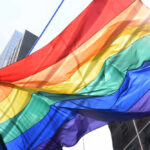 Public Decency Clash: Rainbow Flag Targeted A vibrant rainbow flag waving against a city backdrop