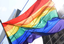 Public Decency Clash: Rainbow Flag Targeted A vibrant rainbow flag waving against a city backdrop