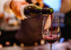 A bartender pouring red wine into a glass