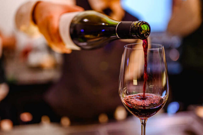 Pouring,Glass,Of,Red,Wine,From,A,Bottle. A bartender pouring red wine into a glass