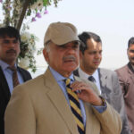 Ceasefire Hangs On Islamabad’s Whisper Network A group of men in formal attire at an outdoor event, with one man wearing a cap