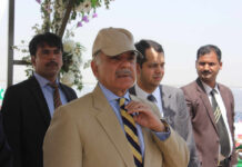 Ceasefire Hangs On Islamabad’s Whisper Network A group of men in formal attire at an outdoor event, with one man wearing a cap
