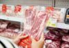A man stands in front of empty meat shelves in a grocery store