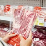 A man stands in front of empty meat shelves in a grocery store
