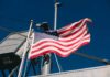 AI Lifeboat Dares Iran’s Doorstep A naval destroyer displaying the American flag and various signal flags
