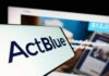 Fifth-Fest Erupts at ActBlue Hearing Close-up of a mobile device displaying the ActBlue logo with a blurred background of a fundraising website