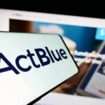 Fifth-Fest Erupts at ActBlue Hearing Close-up of a mobile device displaying the ActBlue logo with a blurred background of a fundraising website