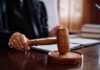 Virginia Muzzles ICE — DOJ Takes It To Court A judge's hand holding a gavel in a courtroom setting