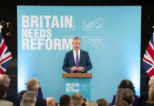 Musk Backs Farage Rival — Could Hand Labour Victory A politician delivering a speech at a podium with British flags in the background
