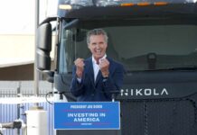 Newsom Taunts: ‘Maybe Trillionaire’ Musk A speaker passionately addressing an audience in front of an electric truck