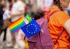 Eastern Clergy Challenge Pride Push A person with a purple backpack displaying a rainbow flag and an EU flag