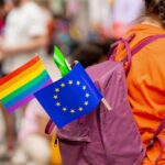 Eastern Clergy Challenge Pride Push A person with a purple backpack displaying a rainbow flag and an EU flag