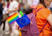 Eastern Clergy Challenge Pride Push A person with a purple backpack displaying a rainbow flag and an EU flag