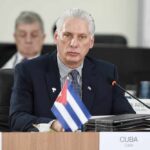 Communist Cuba Blinks — Panic Reboot Cuban representative at a political meeting with a flag on the table