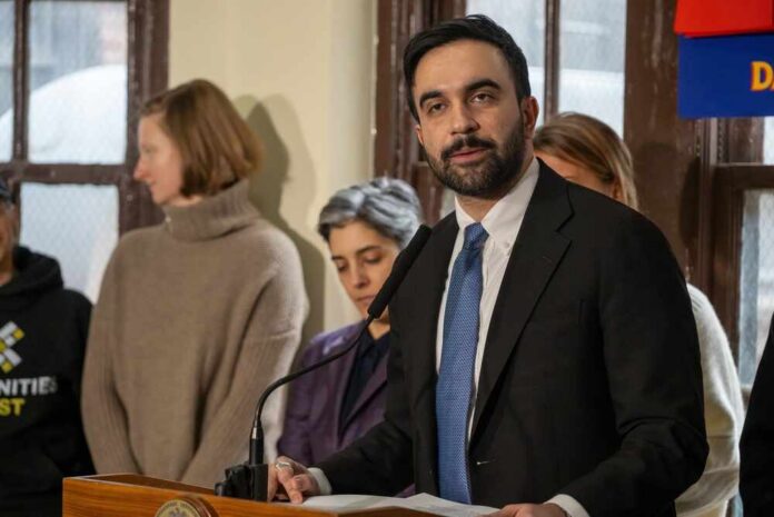 Man in suit speaking at a podium with people standing behind