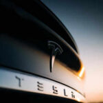 Closeup of Tesla car logo at sunset