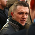 Heathrow Shock: Counter-Terror Dragnet Man speaking intensely in a crowded outdoor setting