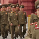 Military officers marching together in uniform.
