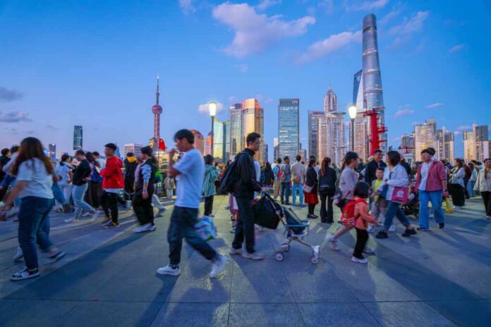 Shanghai,,China,-,October,3rd,2024:,People,Take,Walking,On Crowd walking on a riverside promenade at dusk with modern skyline in background