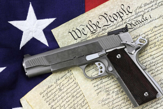 gun-21436347 Pistol on Constitution and flag background.