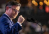Mike Johnson Lights A Voting Firestorm Man speaking at a podium with two microphones.